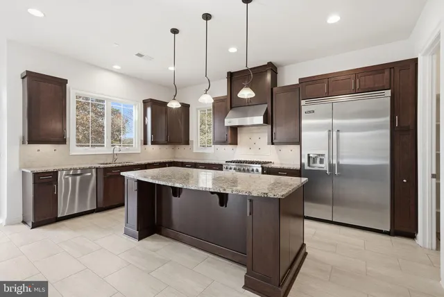 a kitchen with stainless steel appliances granite countertop a sink a stove a refrigerator and island