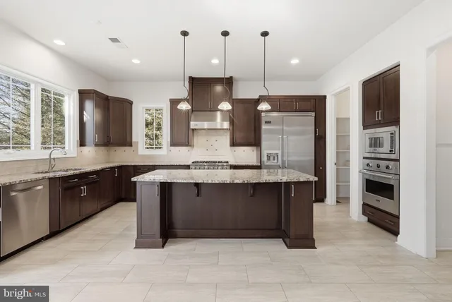a large kitchen with stainless steel appliances granite countertop a stove and a sink