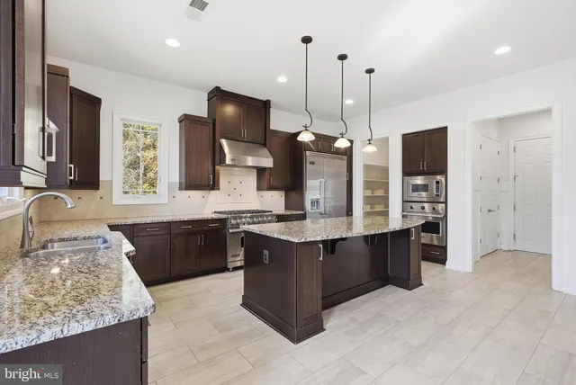 a large kitchen with a stove kitchen island granite countertop a sink counter space and a stove top oven