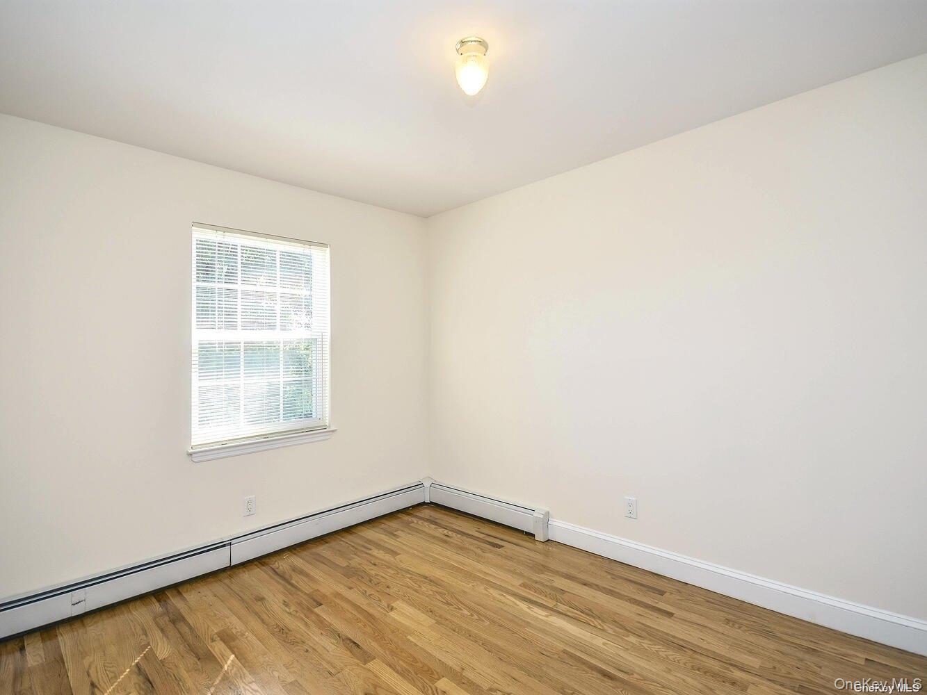 34 Firwood Road, Unit B Port Washington, NY 11050 - Photo 14 of 25 an empty room with wooden floor and windows