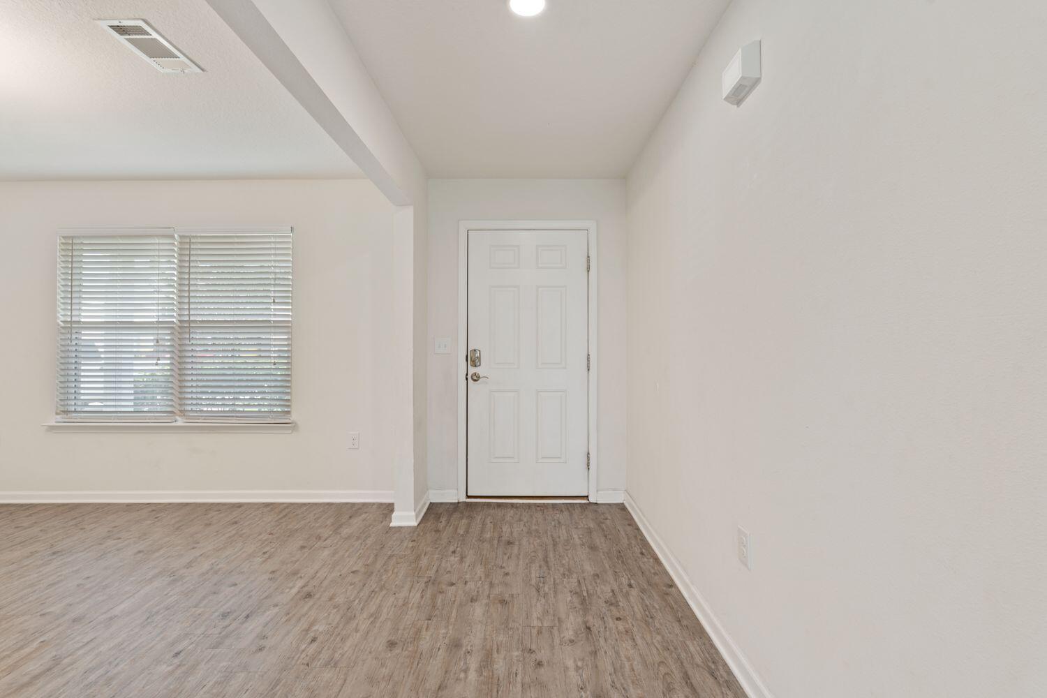 737 Widgeon Way Crestview, FL 32539 - Photo 7 of 36 an empty room with wooden floor and windows