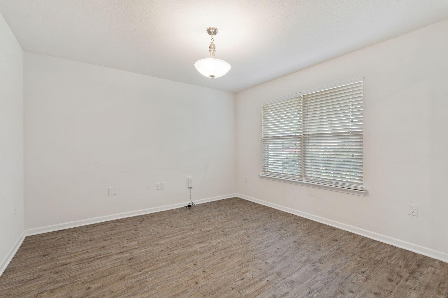 737 Widgeon Way Crestview, FL 32539 - Photo 8 of 36 an empty room with wooden floor and windows