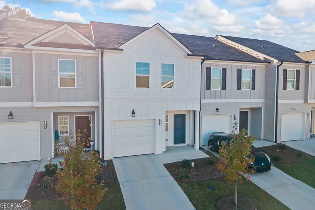 a view of a white house with potted plants next to a yard
