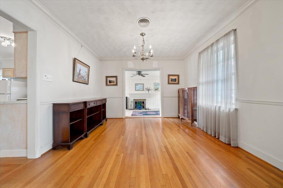 5280 Cole Road Memphis, TN 38120 - Photo 11 of 31 Unfurnished dining area featuring a chandelier, light wood finished floors, a fireplace, ornamental molding, and ceiling fan