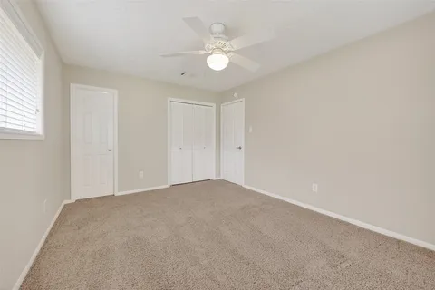 an empty room with a ceiling fan and a window