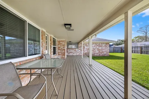a view of a patio with table and chairs with wooden floor and fence