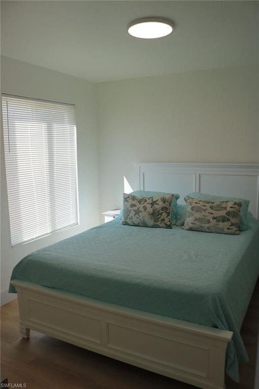 2235 San Marco Road, Unit 5204 Marco Island, FL 34145 - Photo 18 of 34 Bedroom featuring light-tone wood-finish flooring, a window with blinds, and a ceiling-mounted light fixture