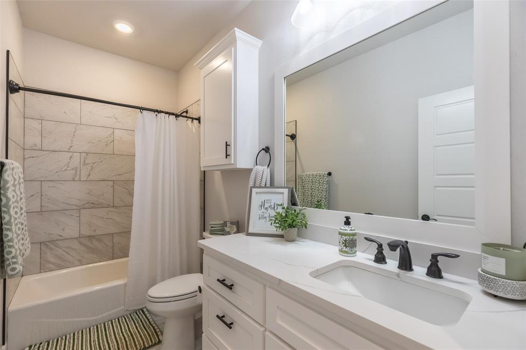 107 Kleingrass Road Abilene, TX 79606 - Photo 24 of 33 Bathroom featuring a tub/shower combination with large format tile surround, a white vanity with integrated sink, and a framed mirror