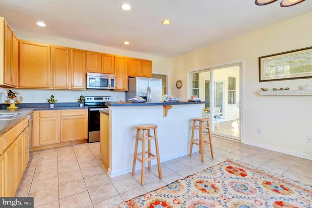 a kitchen with stainless steel appliances granite countertop a table chairs sink and cabinets
