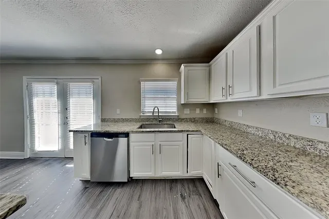 a kitchen with stainless steel appliances granite countertop a sink and wooden floors