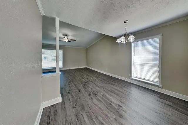 an empty room with wooden floor and chandelier