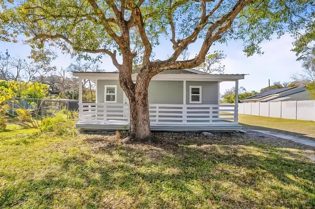 a view of a house with a large tree and a yard