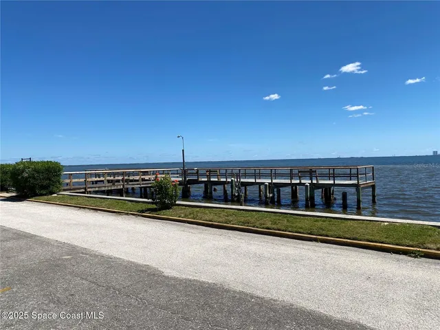 a view of a large pool with lawn chairs and wooden fence