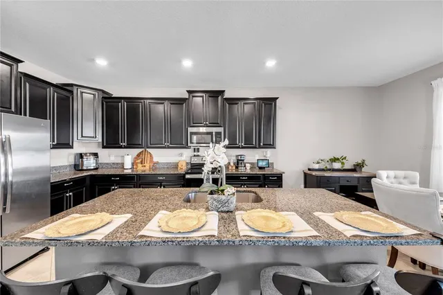 a kitchen with sink refrigerator dining table and chairs