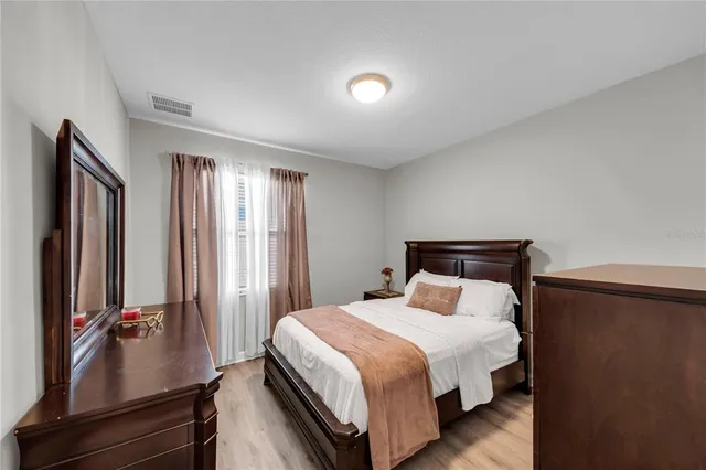 a bedroom with a bed and a flat tv screen on a dresser