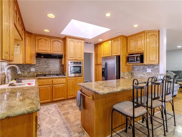 a kitchen with stainless steel appliances granite countertop sink microwave and wooden cabinets