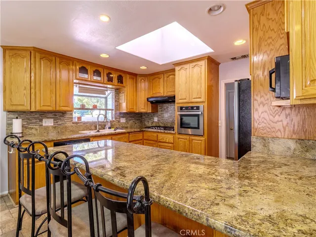 a kitchen with stainless steel appliances granite countertop a stove top oven a sink and cabinets
