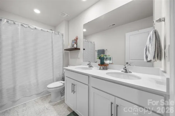 a bathroom with a double vanity sink toilet and a mirror