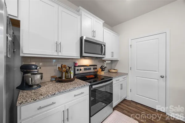 a kitchen with granite countertop white cabinets stainless steel appliances and a sink