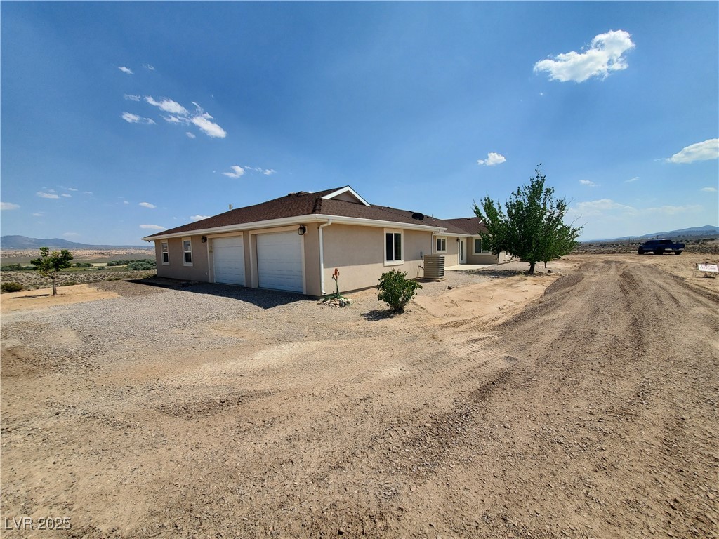 5272 Truman Lane Caliente, NV 89008 - Photo 29 of 39 Ranch-style home with stucco siding, a garage, and dirt driveway