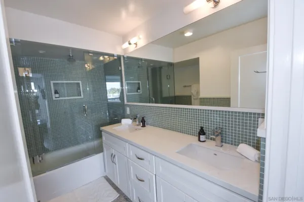 a bathroom with a sink double vanity granite tub shower and a mirror