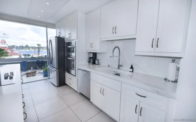 a kitchen with stainless steel appliances granite countertop a sink refrigerator and cabinets
