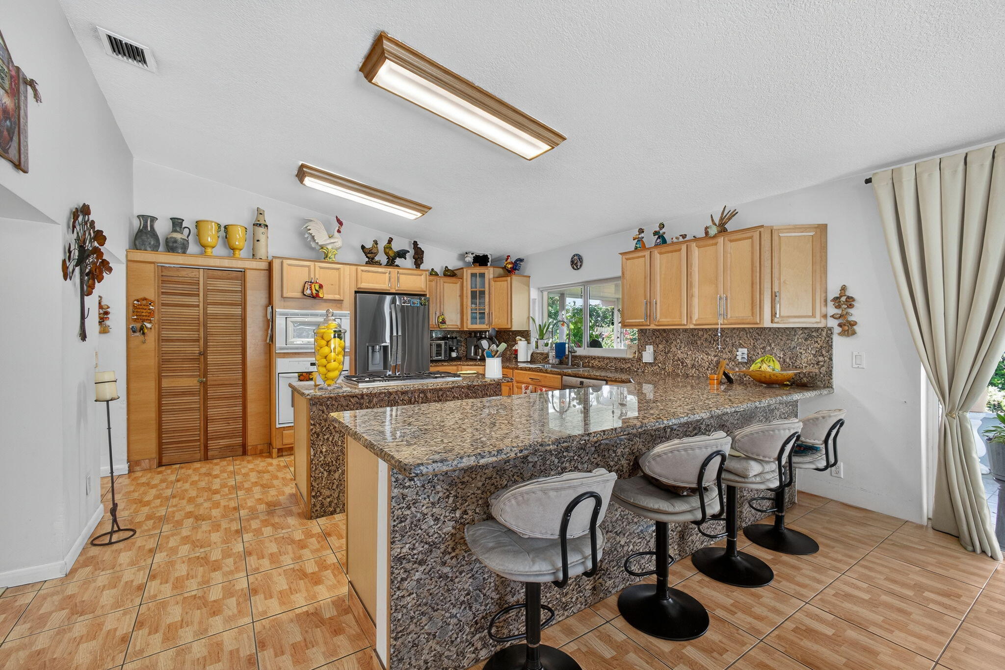 7625 Clarke Road Lake Clarke Shores, FL 33406 - Photo 28 of 97 a kitchen with stainless steel appliances granite countertop a table chairs and a refrigerator
