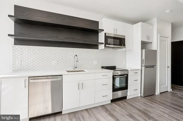 a kitchen with stainless steel appliances a sink dishwasher a refrigerator and wooden floor