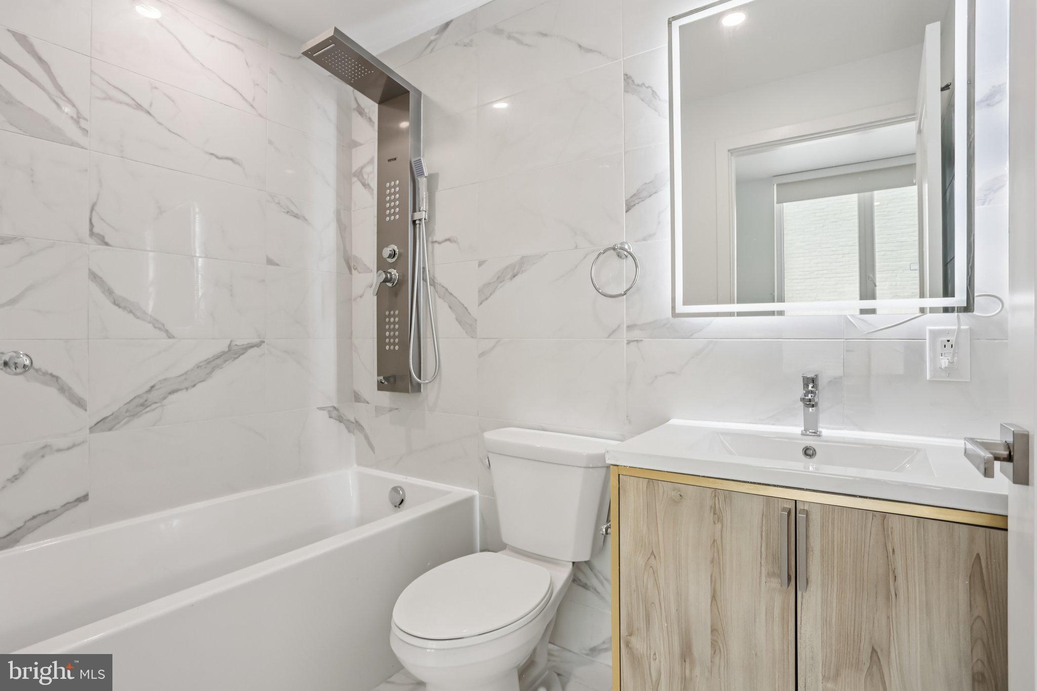1201 Vine Street, Unit 2 Philadelphia, PA 19107 - Photo 5 of 31 a bathroom with a toilet a sink a mirror a bathtub and shower