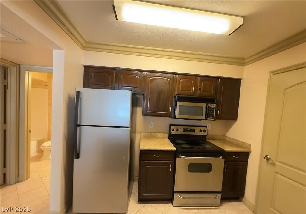 8101 West Flamingo Road, Unit 1082 Las Vegas, NV 89147 - Photo 11 of 23 A compact kitchen offering all essential appliances with rich wooden cabinetry.