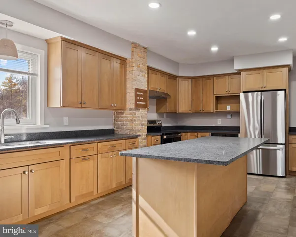 a view of an empty room with wooden floor fireplace and a window