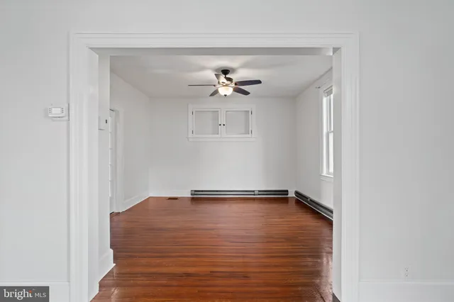 a view of an empty room with a window and wooden floor