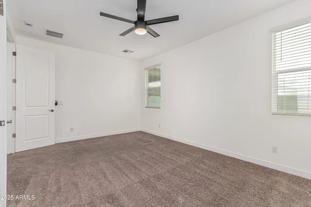 an empty room with windows and fan