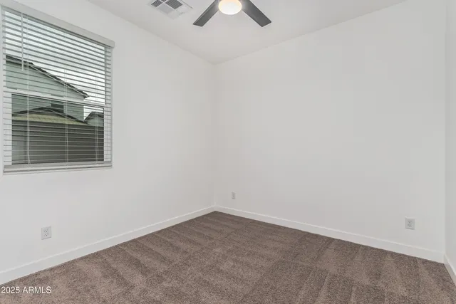 an empty room with a window and a ceiling fan