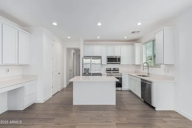 a large kitchen with stainless steel appliances granite countertop a large center island a stove a sink dishwasher and a refrigerator with wooden floor