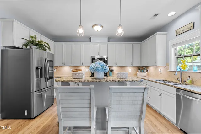 a kitchen with kitchen island granite countertop a sink cabinets and stainless steel appliances
