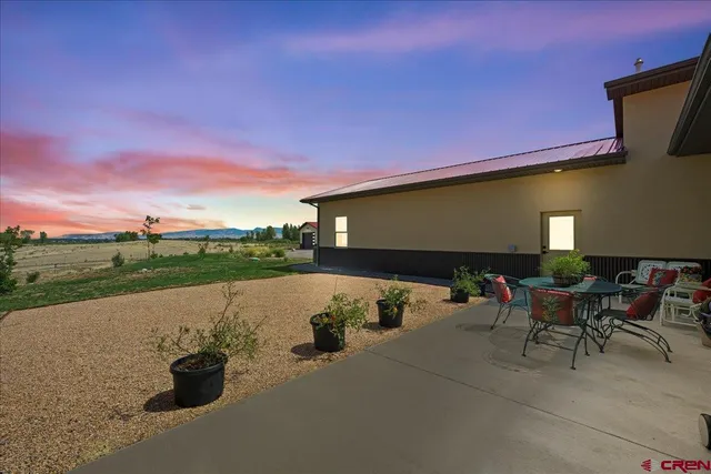 a view of a patio with table and chairs under an umbrella next to a yard