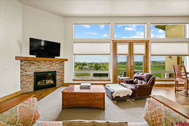 a living room with furniture a fireplace and floor to ceiling windows