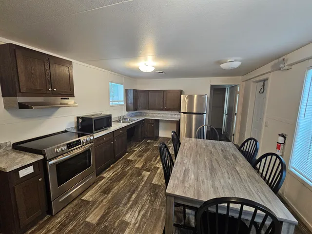 a kitchen with granite countertop a stove a sink dishwasher a dining table and chairs