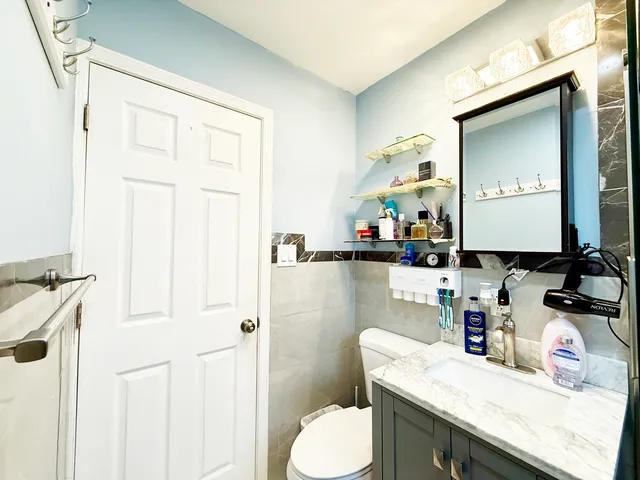a bathroom with a granite countertop sink a toilet and a mirror