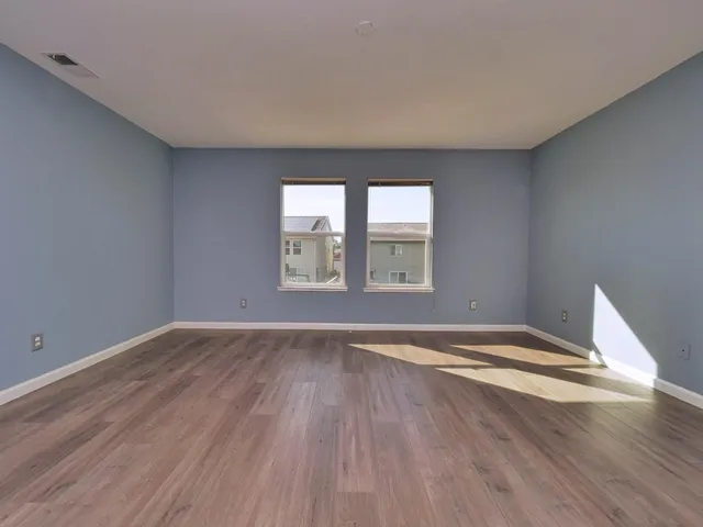 an empty room with wooden floor and windows