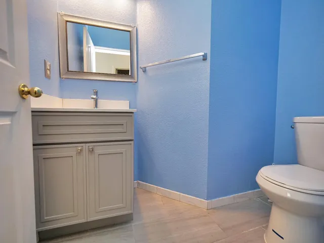 a bathroom with a toilet sink vanity and mirror