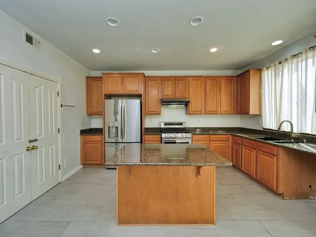 a large kitchen with stainless steel appliances granite countertop a refrigerator and a stove top oven