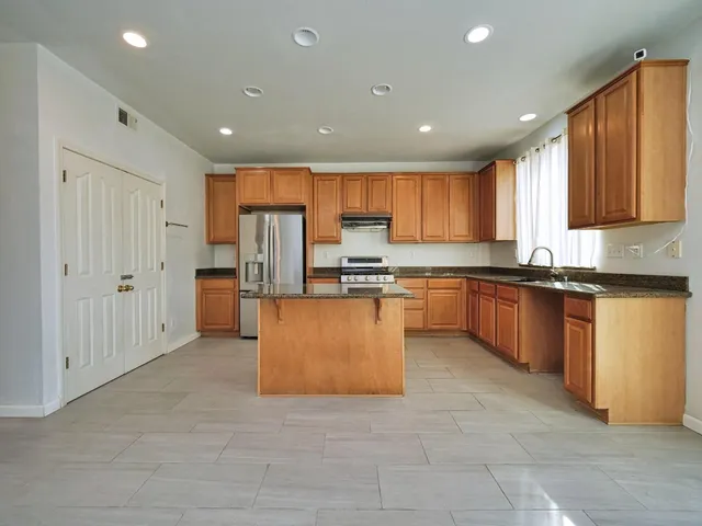 a large kitchen with granite countertop a large counter top stainless steel appliances and cabinets