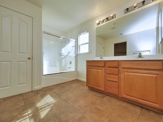 a spacious bathroom with a granite countertop sink mirror and shower