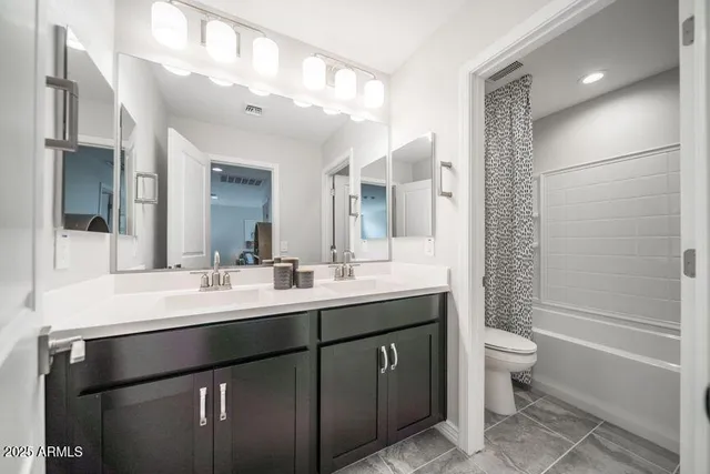 a bathroom with a double vanity sink toilet and shower