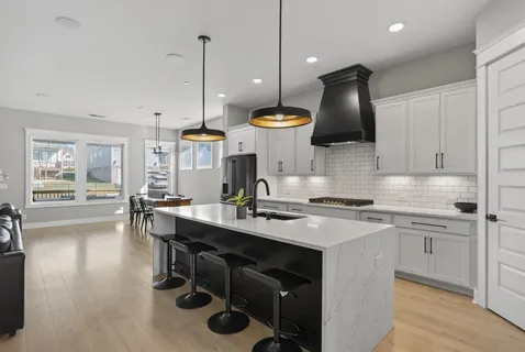 a kitchen with stainless steel appliances granite countertop a stove a sink a oven a dining table and chairs with wooden floor