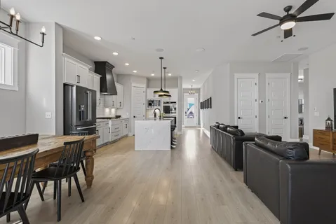 a kitchen with stainless steel appliances kitchen island granite countertop a refrigerator a stove a sink a dining table and chairs with wooden floor