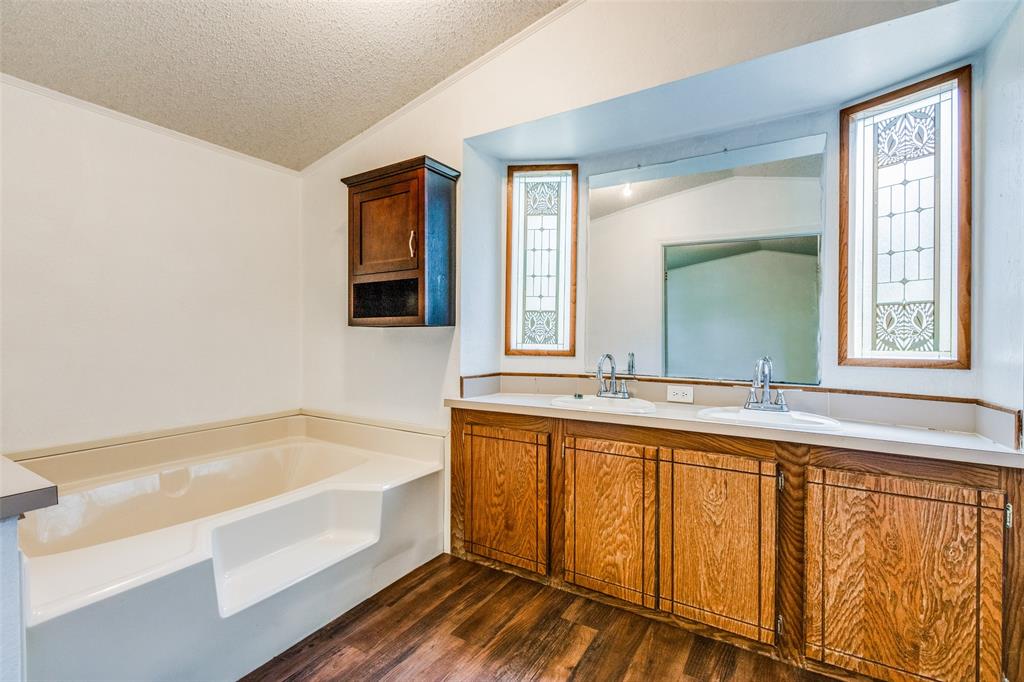 28 Wembley Road Gordonville, TX 76245 - Photo 10 of 24 Ensuite Bathroom featuring vaulted ceiling, hardwood/ wood-style floors, plenty of natural light, double sinks with large vanity and a large soaking tub.