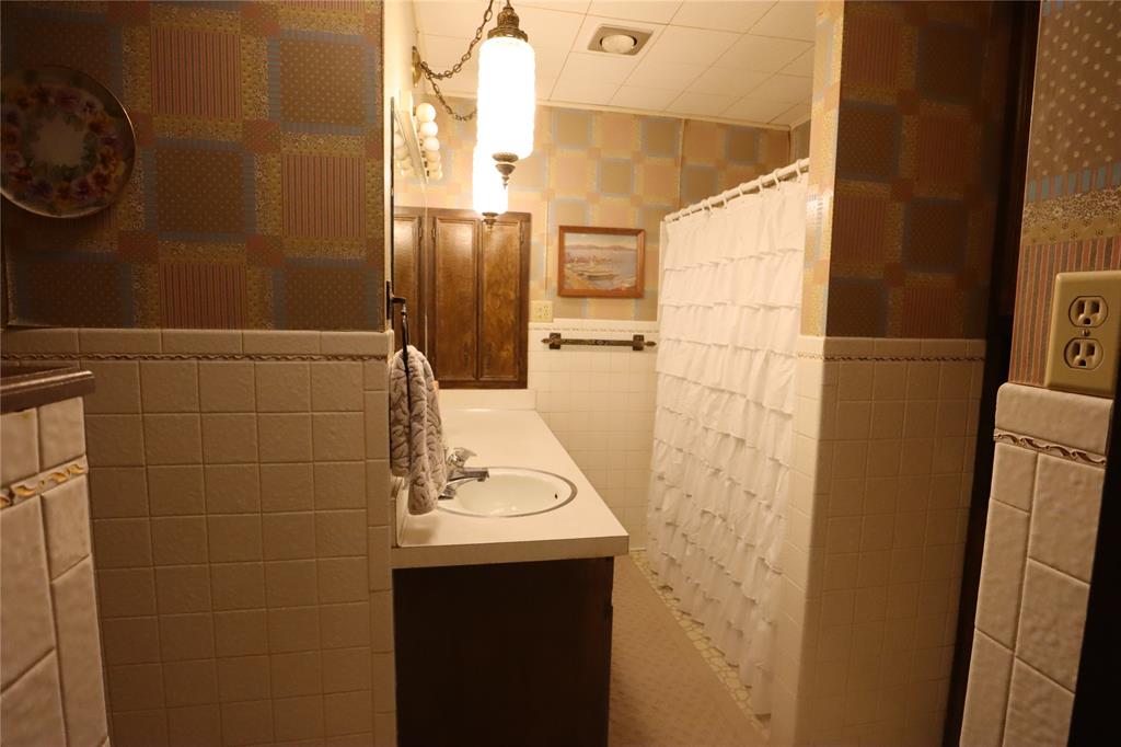 301 Travis Street Ranger, TX 76470 - Photo 19 of 31 a bathroom with a sink a toilet and shower